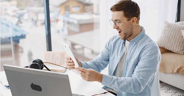 Man using laptop and tablet to sign up for contact lens subscription on his eye doctor's website